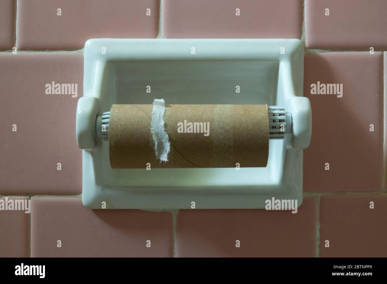 Empty toilet paper roll tube on the wall holder Stock Photo