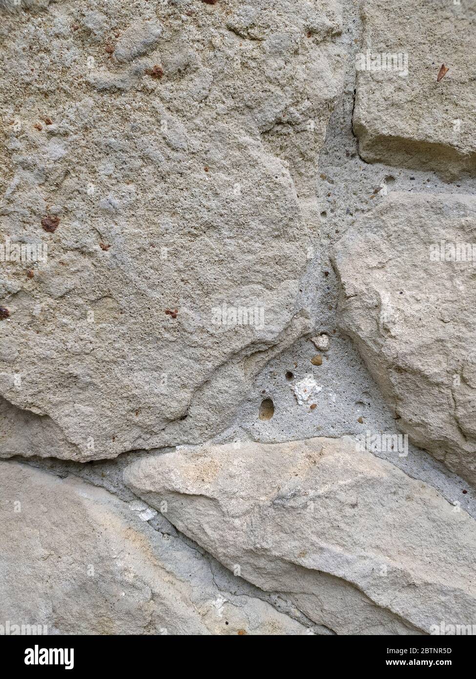Gray stone wall background, mosaic stonewall rubble facade closeup