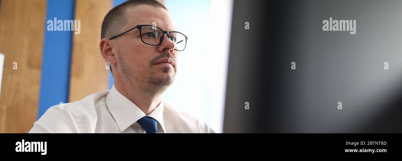 Confident and pensive man working with computer at workplace Stock Photo