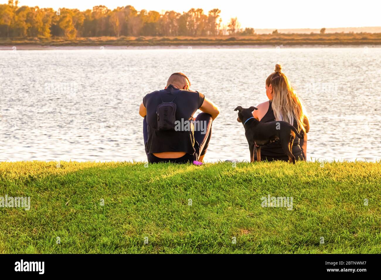 Couple sitting on the grass and enjoying the sunset Stock Photo