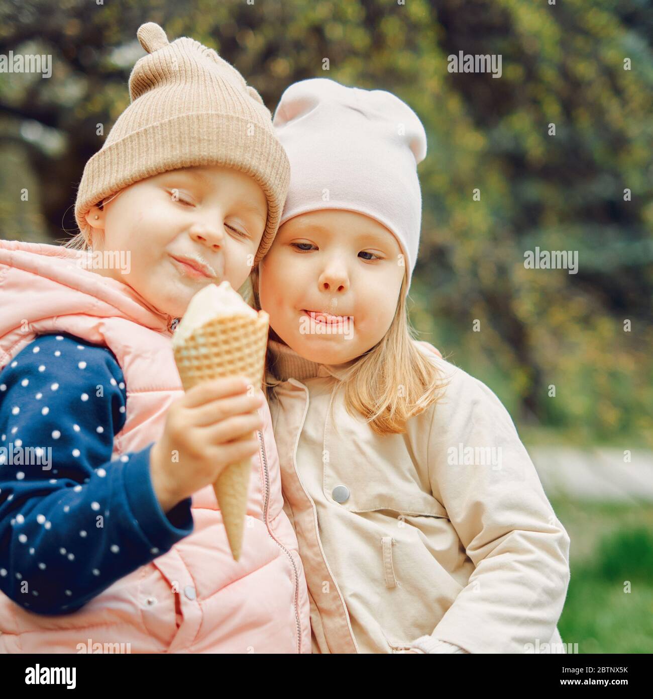 2 little girls 3 years old eating ice cream together in the park Stock