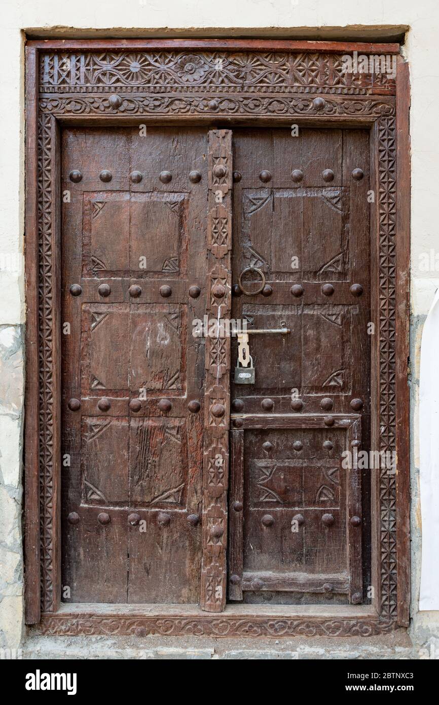 Traditionally carved Omani wooden door in dark brown color, seen in Nizwa Stock Photo