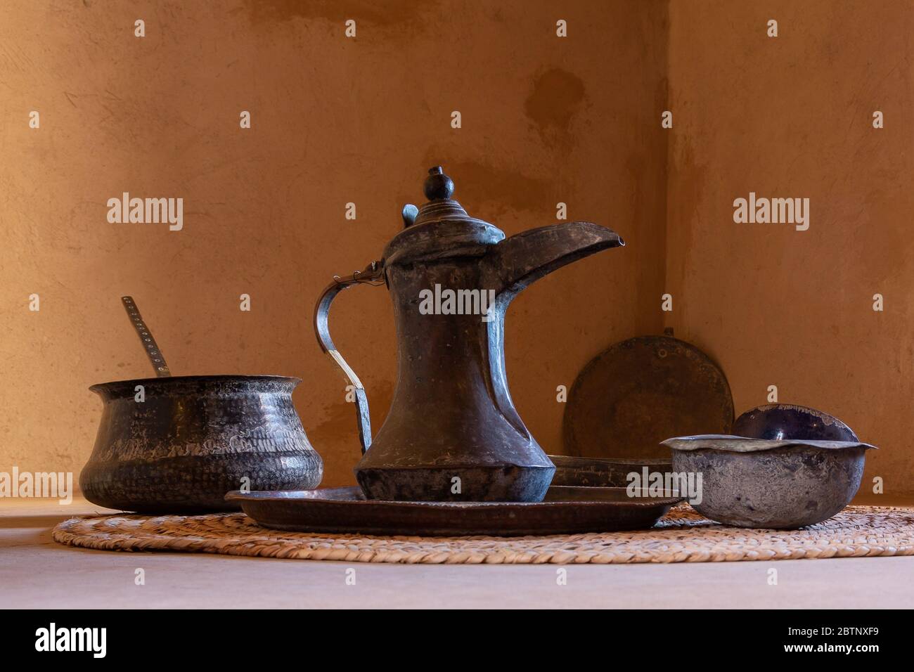 Omani style coffee pot called dallah and bowls in front of brown clay wall, Nizwa Stock Photo