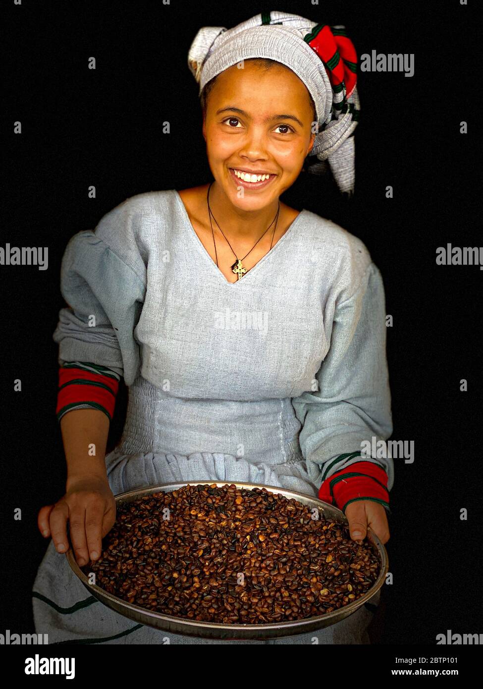 Young Afar woman with traditional clothing showing roasted coffee beans, Ethiopia, Africa Stock Photo
