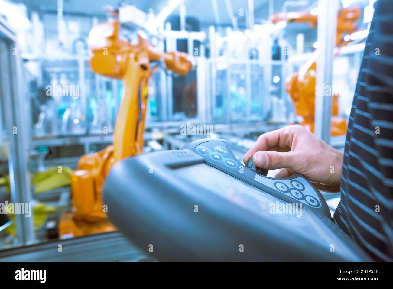 Young man programming industrial automatic robot in the automotive industry, industrial concept Stock Photo