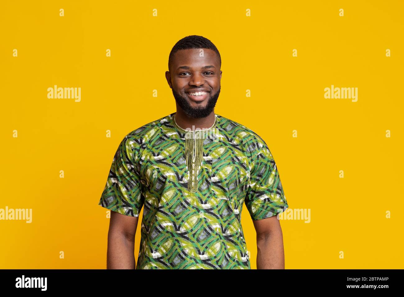 African man in green authentic clothes posing over yellow background Stock Photo