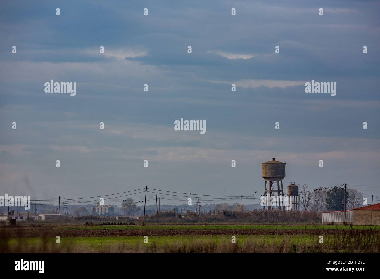 Hazy midday hot daytime landscape from far away with haze of village of Nea Kessani, Xanthi region, Northern Greece with water tower and industrial zone Stock Photo