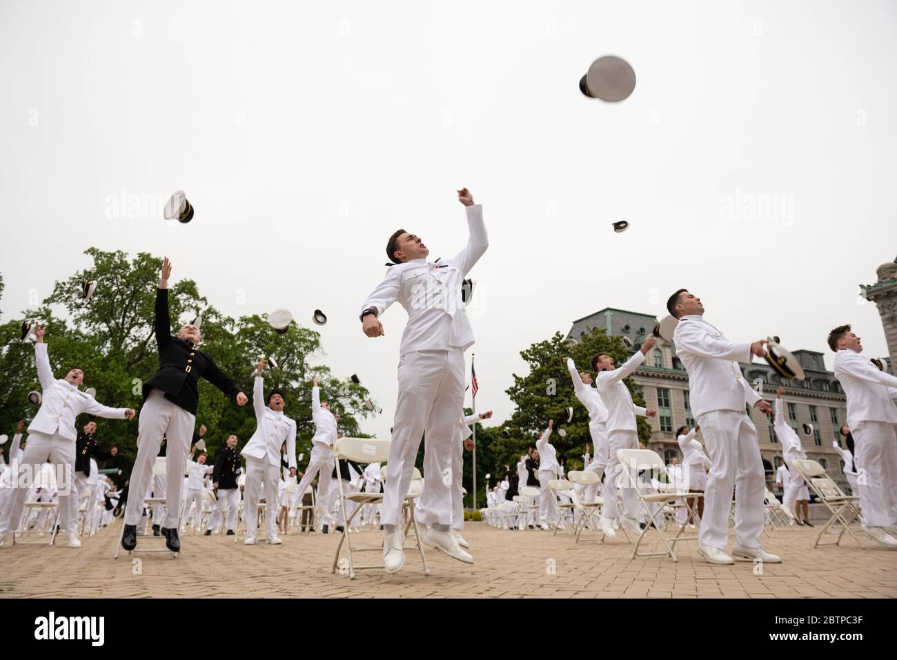 U.S. Naval Academy midshipmen toss their hats into the air at the conclusion of the commencement and commissioning ceremony for the Naval Academy Class of 2020 under COVID-19, coronavirus pandemic social distancing rules May 18, 2020 in Annapolis, Maryland. Approximately 1,000 midshipmen will graduate and be sworn-in during five events and one virtual ceremony. Stock Photo