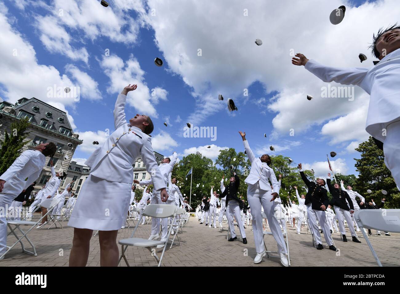 U.S. Naval Academy midshipmen toss their hats into the air at the conclusion of the commencement and commissioning ceremony for the Naval Academy Class of 2020 under COVID-19, coronavirus pandemic social distancing rules May 16, 2020 in Annapolis, Maryland. Approximately 1,000 midshipmen will graduate and be sworn-in during five events and one virtual ceremony. Stock Photo