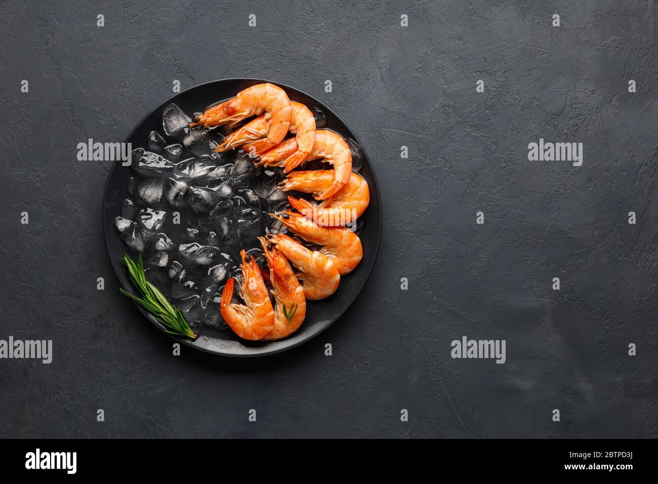Fresh raw shrimp with ice on a black stone background. Seafood. Top ...