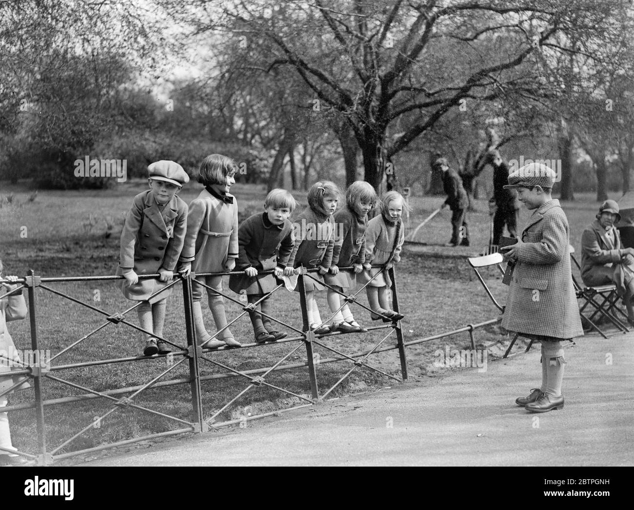 Snapped in the Park . A group of society children pose for their pictures in the sunshine in Hyde Park . Left to right : Richard Cecil Law , Rachael Shiff , the Hon Michael Healy Hutchinson , Susan Carbutt , Diana Carbutt , Angela Rutter , being photographed by Ruari Hillory . 5 April 1932 Stock Photo