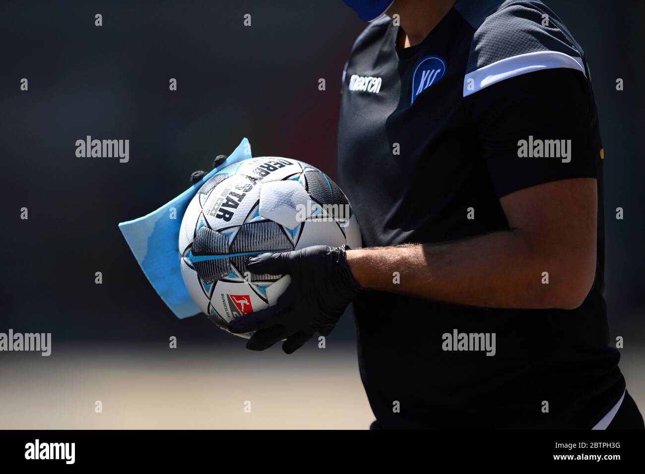 A ball boy disinfects a ball during the 2nd Bundesliga soccer match between Karlsruher SC and SV Darmstadt 98, in Karlsruhe, Germany, Saturday, May 16, 2020. Professional soccer has resumed after a two-month break in Germany with four games in the second division. Stock Photo
