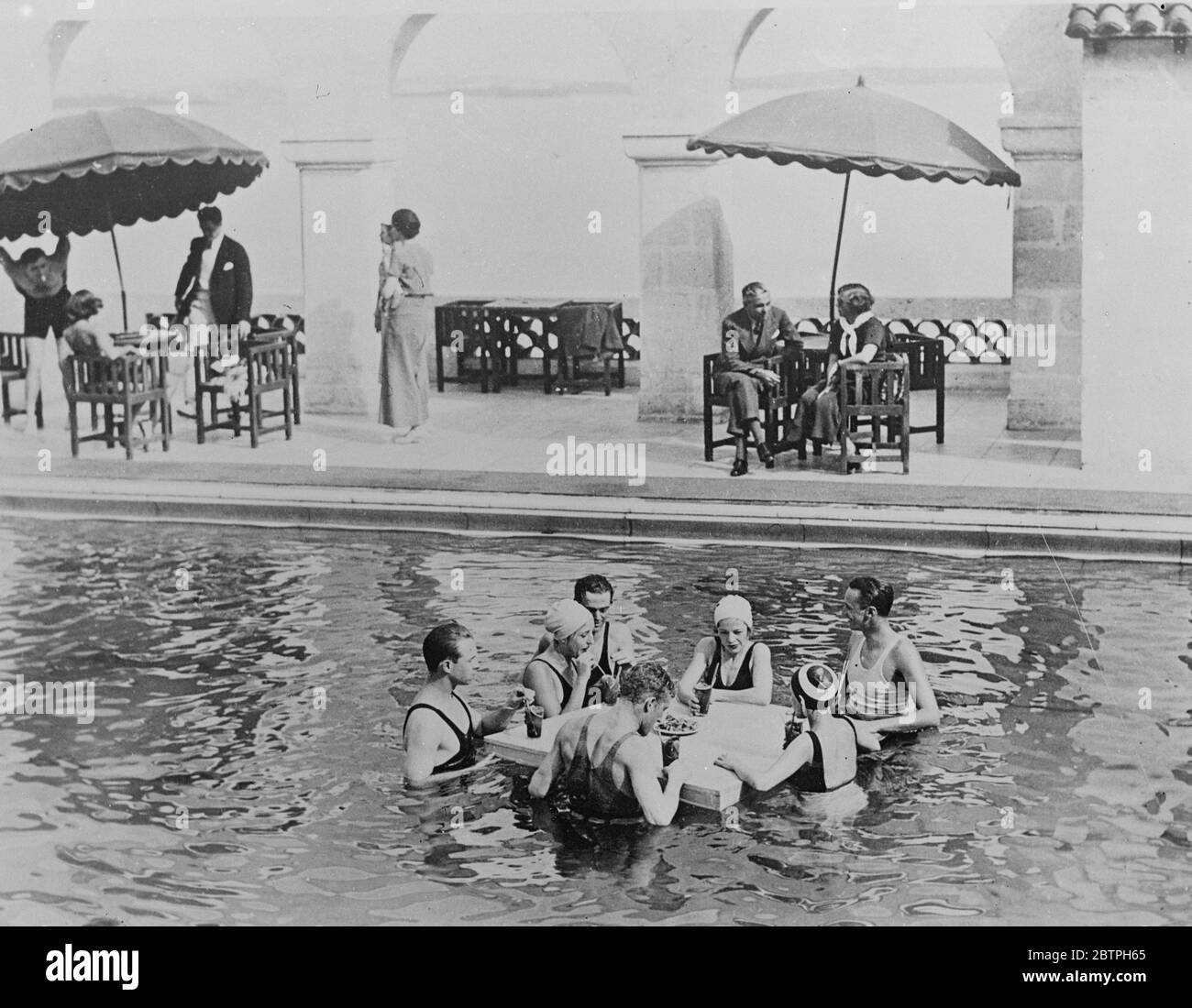 Where summer still reigns . While Britain is freezing Bermuda is enjoying a heat wave . Visitors to Castle harbour , Bermuda enjoying iced drinks in the swimming pool . 2 March 1932 Stock Photo