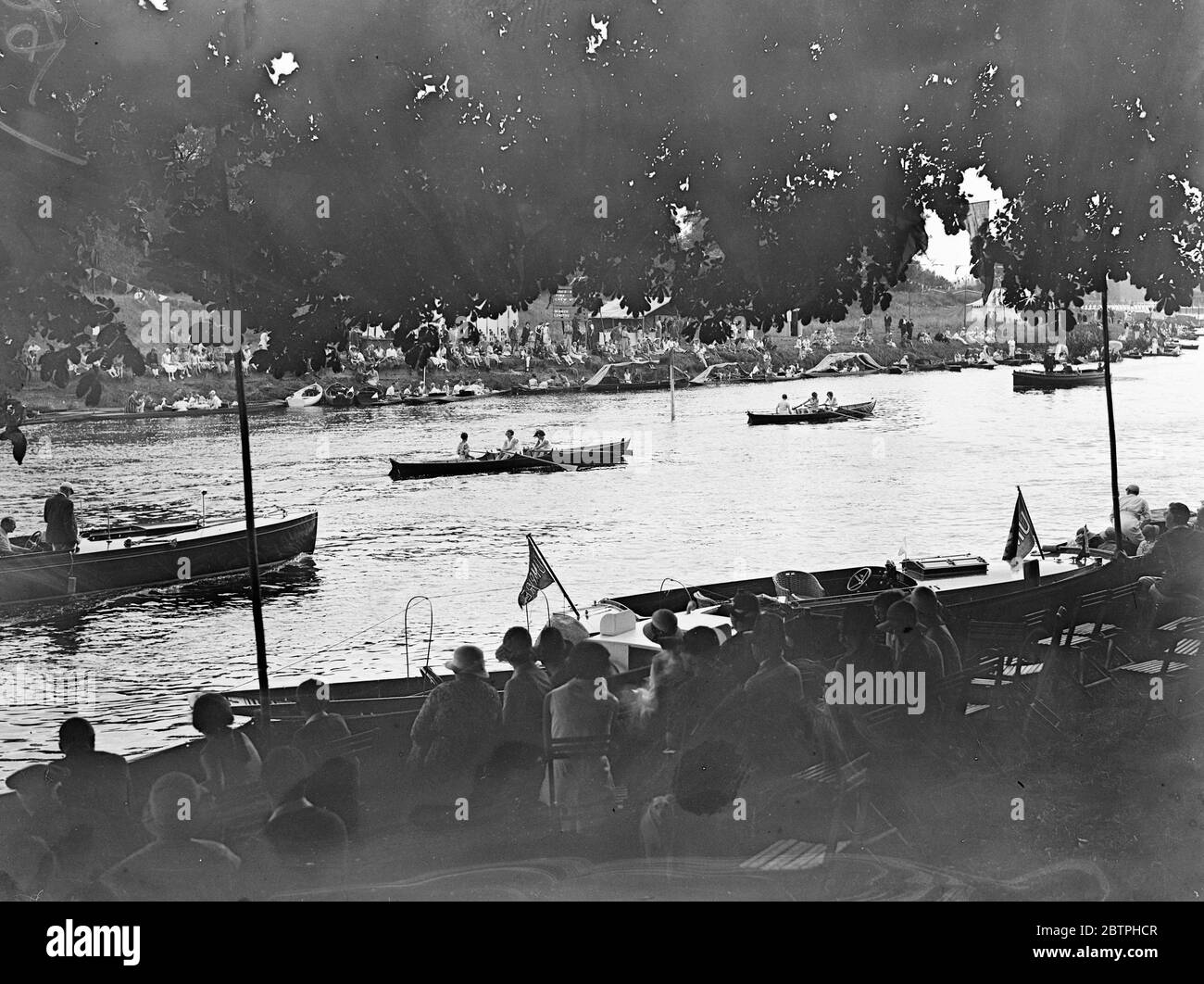 Watching the Teddington regatta . Watching the racing in the Teddington Skiff Regatta , on the Thames from punts beside the bank . 20 August 1932 Stock Photo