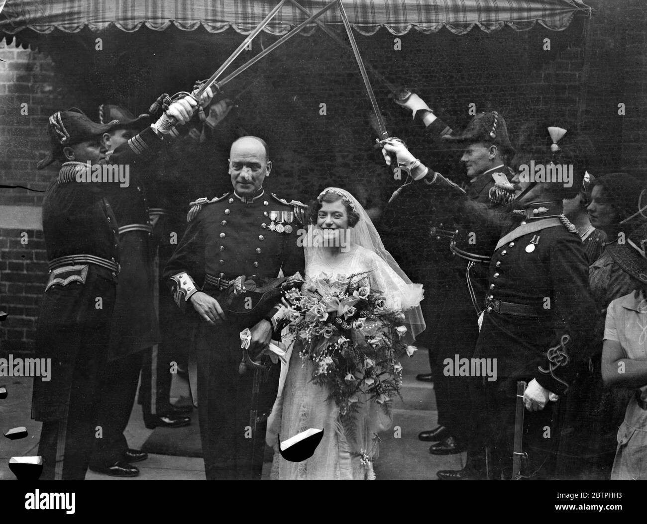 Naval surgeon commander weds . The wedding of Surgeon Commander N A H Barlow , Royal Navy , and Miss Phyllis Ashcraft , took place at Holy Tinity church , Brompton , London . The bride and groom leaving the church through the naval guard of honour after the ceremony . 10 August 1932 Stock Photo