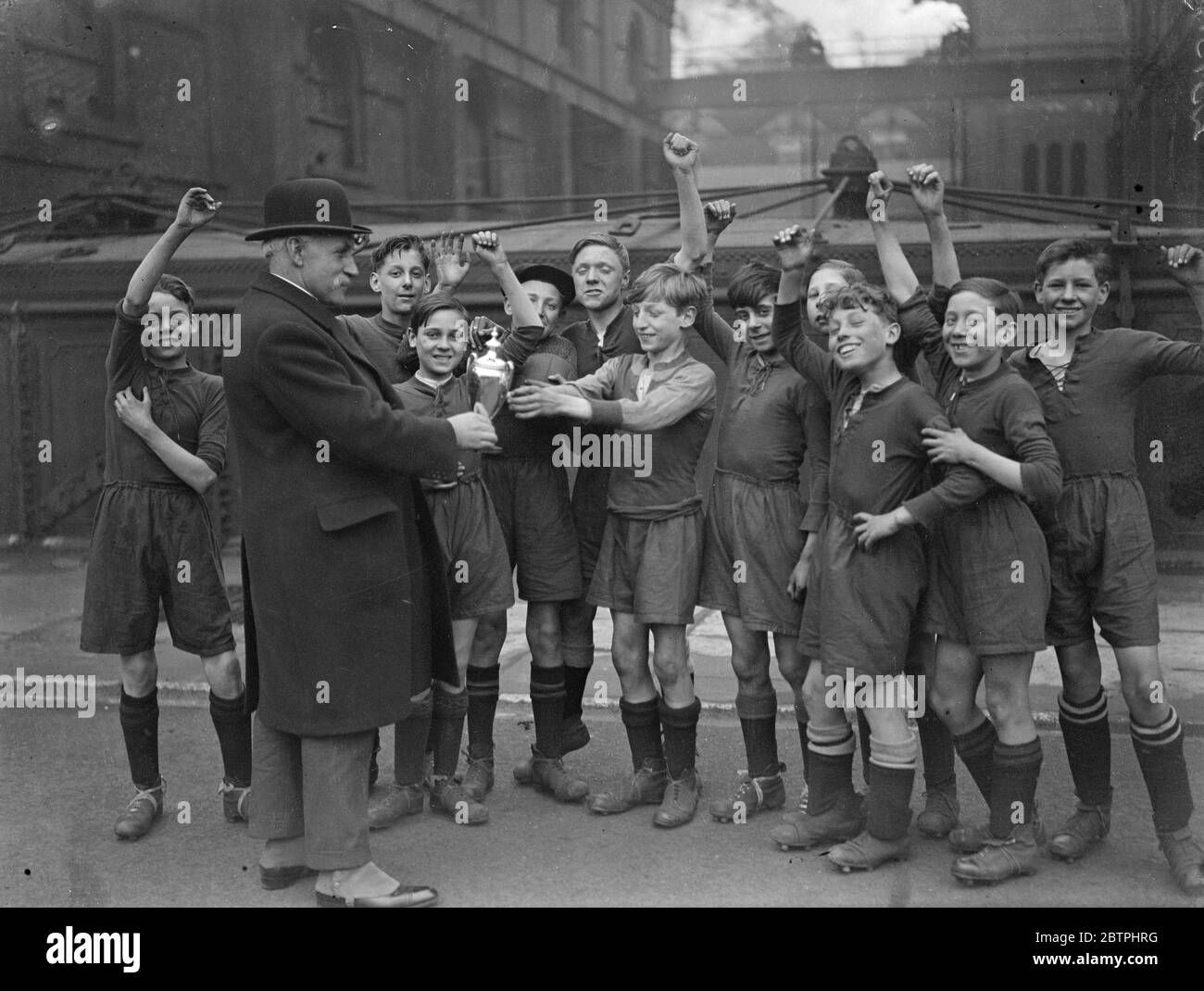 Schoolboys football cup . Boys of the Monteith Road LCC School met boys of the Ricardo Street ( Poplar ) LCC school in the final match for the East End Charity football cup . Boys of the Monteith Road School receiving the trophy from Mr G Teidie after winning the final match . 17 March 1932 Stock Photo