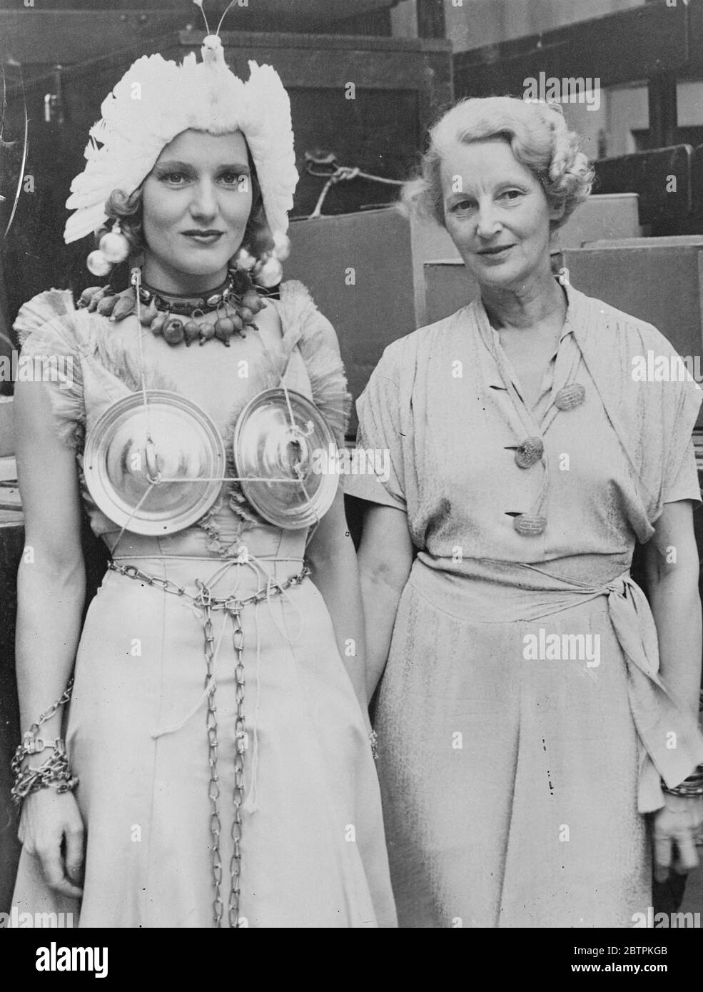 Cleopatra of the Kitchen . Waering a collar and necklace of apples , turnips and onions, and girdled with a light chain , Constance Cummings , the film actress , shows her mother the motley costume she wears in her latest American film . Stock Photo