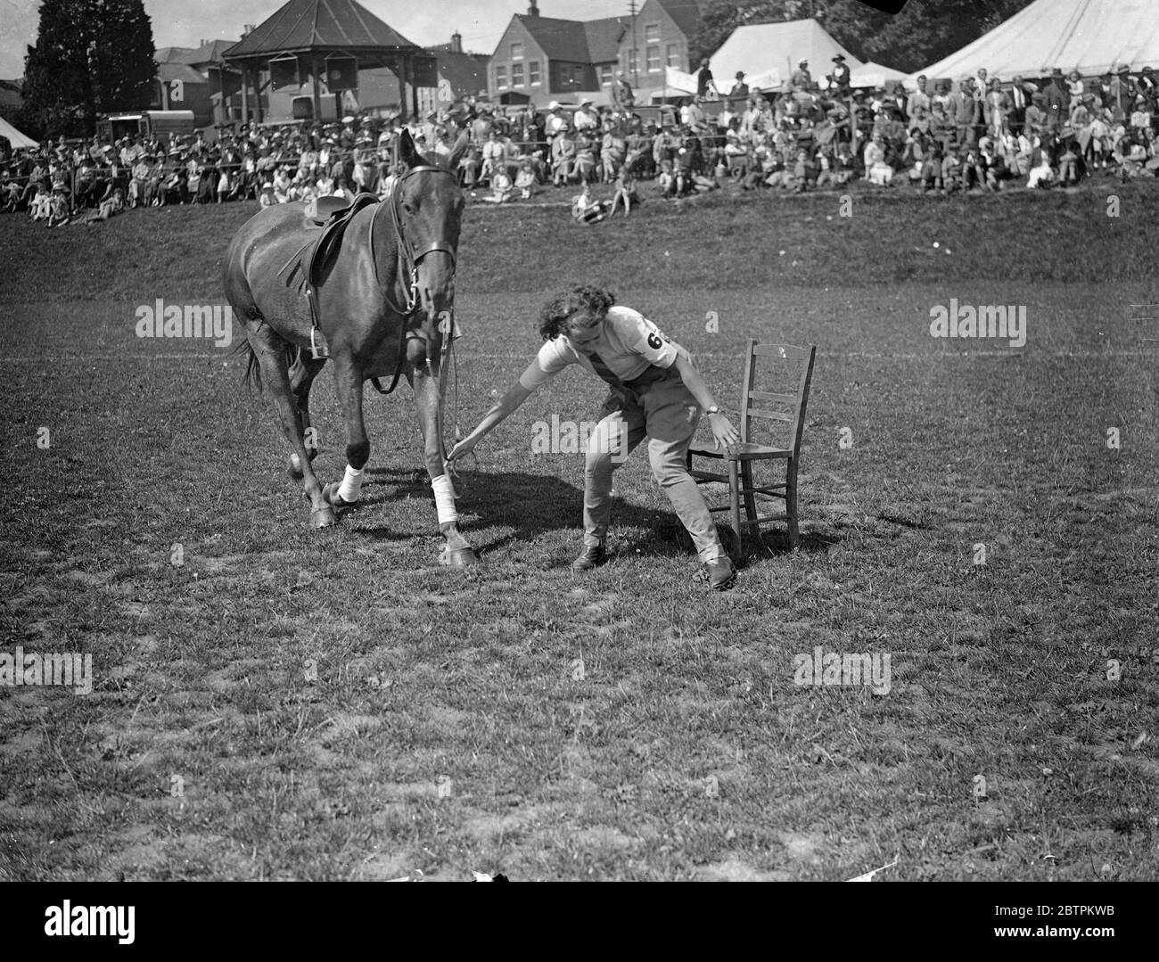 Staking Her Claim ! Photo Shows : Leading her poney , a girl rider eagerly lays claim to a chair as the music ceases during the Musical Chairs competition - one of the many mounted events at the Haywards Heath Horticultural Society ' s summer show in Victoria Park , Haywards Heath , Sussex . 9 Jul 1936 Stock Photo