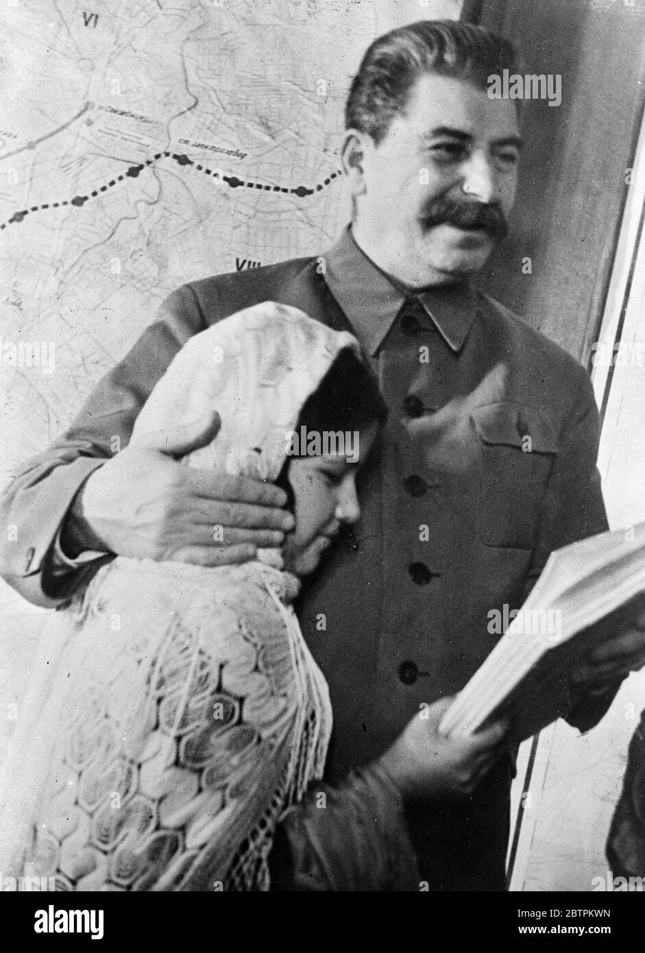 Stalin the paternal . His arm resting affectionately on the cheek of 11 year old Mamlakat Nakhengove , Joseph Stalin , ruler of 160 , 000 , 000 Russians , smilingly receives a copy of the book ' Stalin about Lenin ' in the Tajik language . Mamlekat , a schoolgirl from Tajikistan Republic , travelled specially to Moscow to present her gift to Stalin . 11 December 1935 Stock Photo