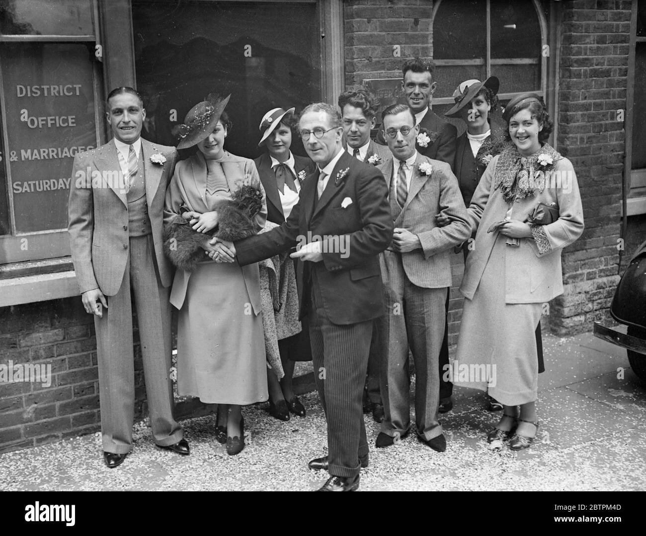 Mass Weddings At Tottenham One of the busiest spots this Whitsun proved to be the Tottenham Register Office , where 40 couples were married by the popular Mr . W . Grimaldi , the Tottenham Registrar . Photo Shows : Mr . Walter Crimaldi congratulating some of the happy couples outside the Register Office . 30 May 1936 Stock Photo