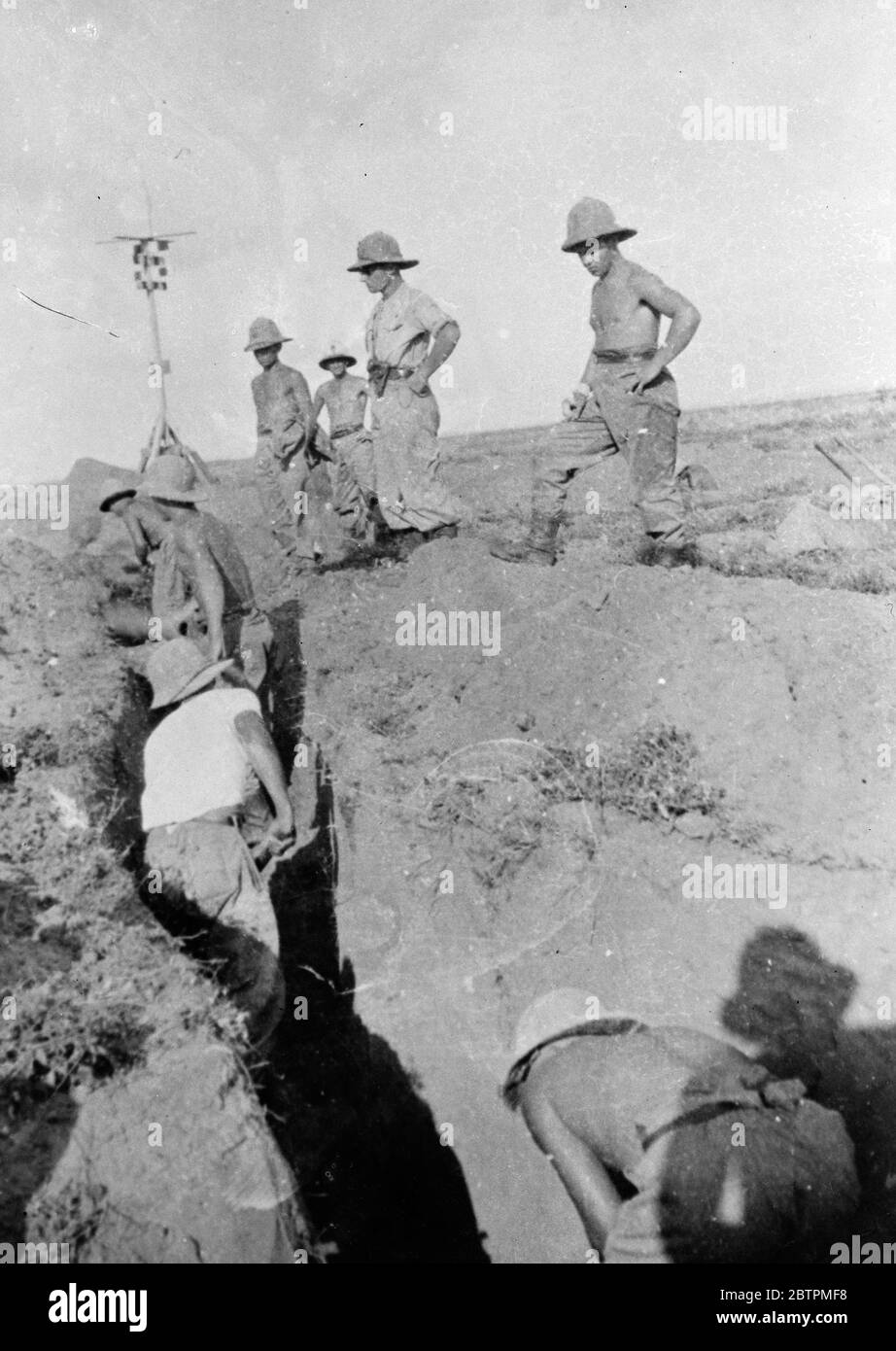 Italians dig themselves in . The Italians mean to hold the territory they have conquered in Abyssinia , and an elaborate system of trenches is being constructed on the fronts to safeguard their positions . Photo shows , Italians digging a trench on their northern front .. 23 November 1935 Stock Photo