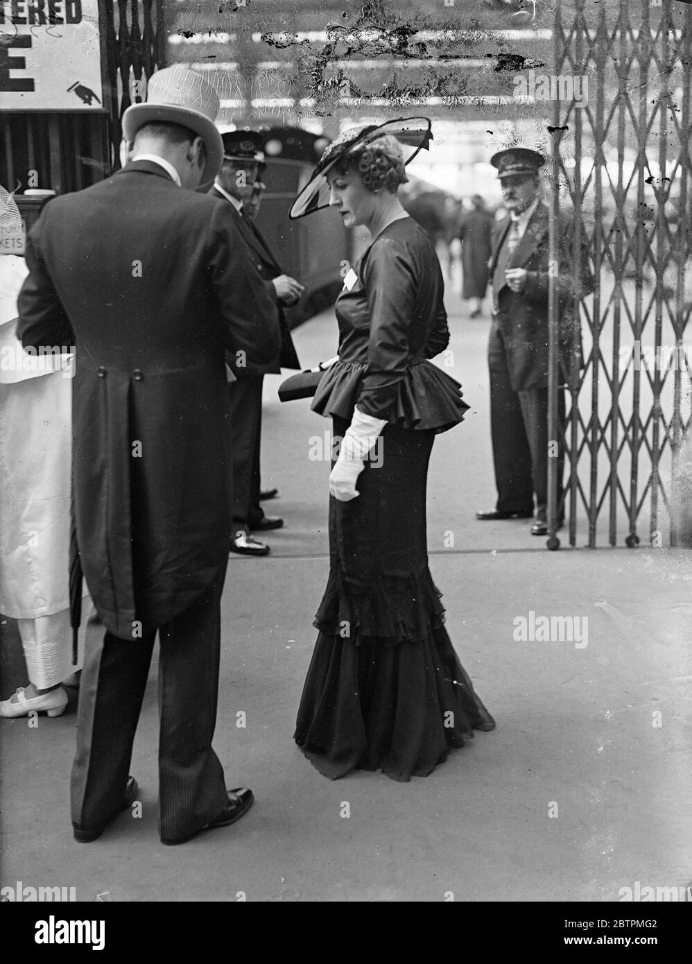Flounces for Ascot . Waterloo Station took on unaccustomed elegance when fashionable crowds left for Ascot , which opens today ( Tuesday ) . Photo shows , a large hat and flounced gown worn by a woman racegoer as she left Waterloo . 16 June 1936 Stock Photo