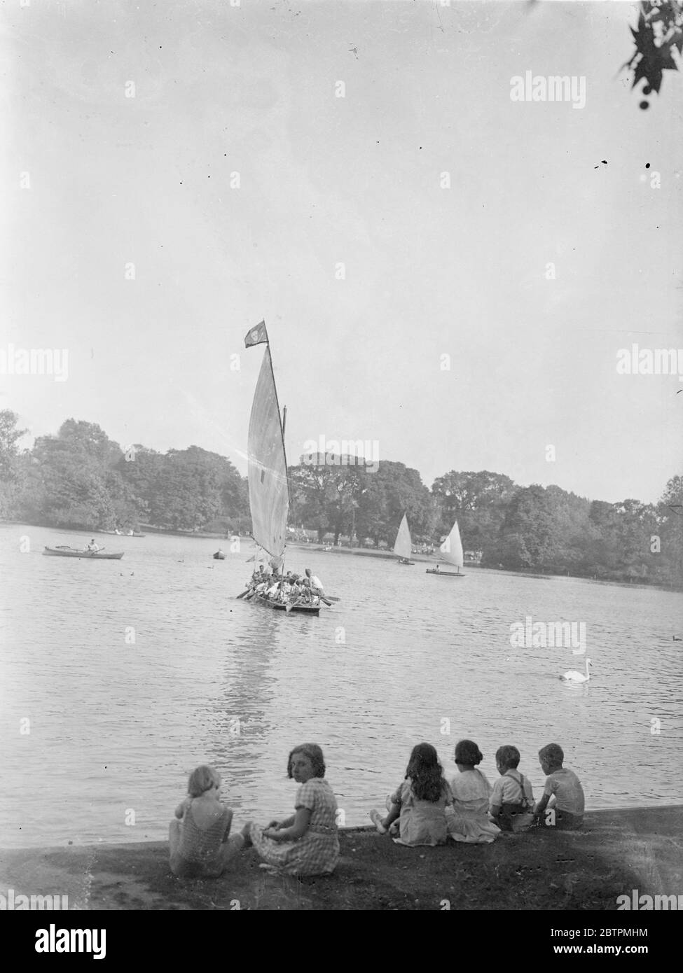 Au Revoir ! Photo shows : Envious eyes turned on a sailing boat on the Regent ' s Park lake as it leaves on a  cruise  in the sunshine . 17 Aug 1936 Stock Photo