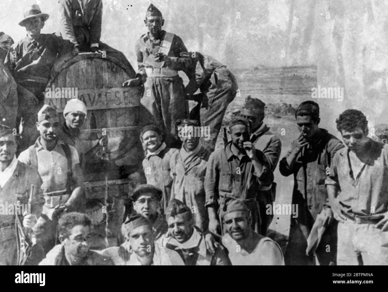 Relief for thirsty warriors . The problem of keeping the Spanish government militia men provided with drinking supplies is being solved on the Aragon front in the North by means of large casks carried from place to place . Photo shows loyalists gathered round a water cask on the Aragon front , 14 September 1936 Stock Photo