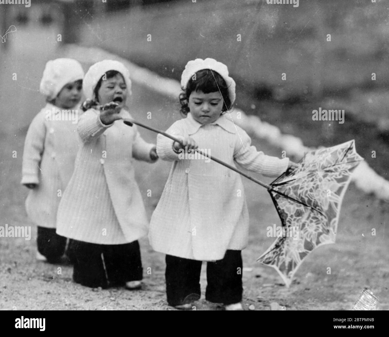Dionnes . Yvonne with the parasol , with tearful Annette , while Marie maintains her neutrality . 22 October 1936 Stock Photo
