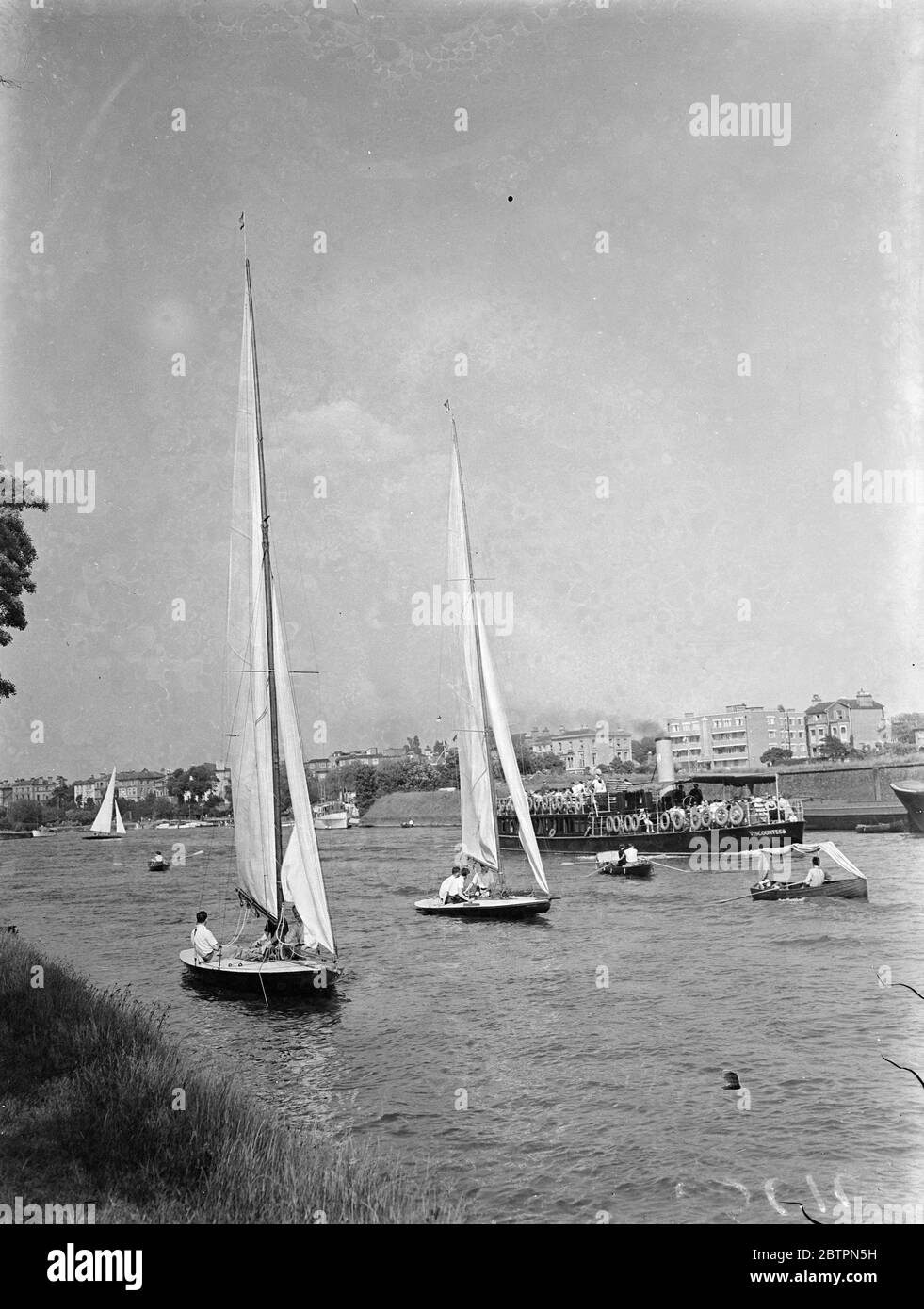 Heatwaves Saturday on the river. Yachts of the Royal Thames Yacht's Club passing serenely over the sun lit Thames at Surbiton where they made a pretty picture for pleasure steamer passengers. 29 May 1937 Stock Photo