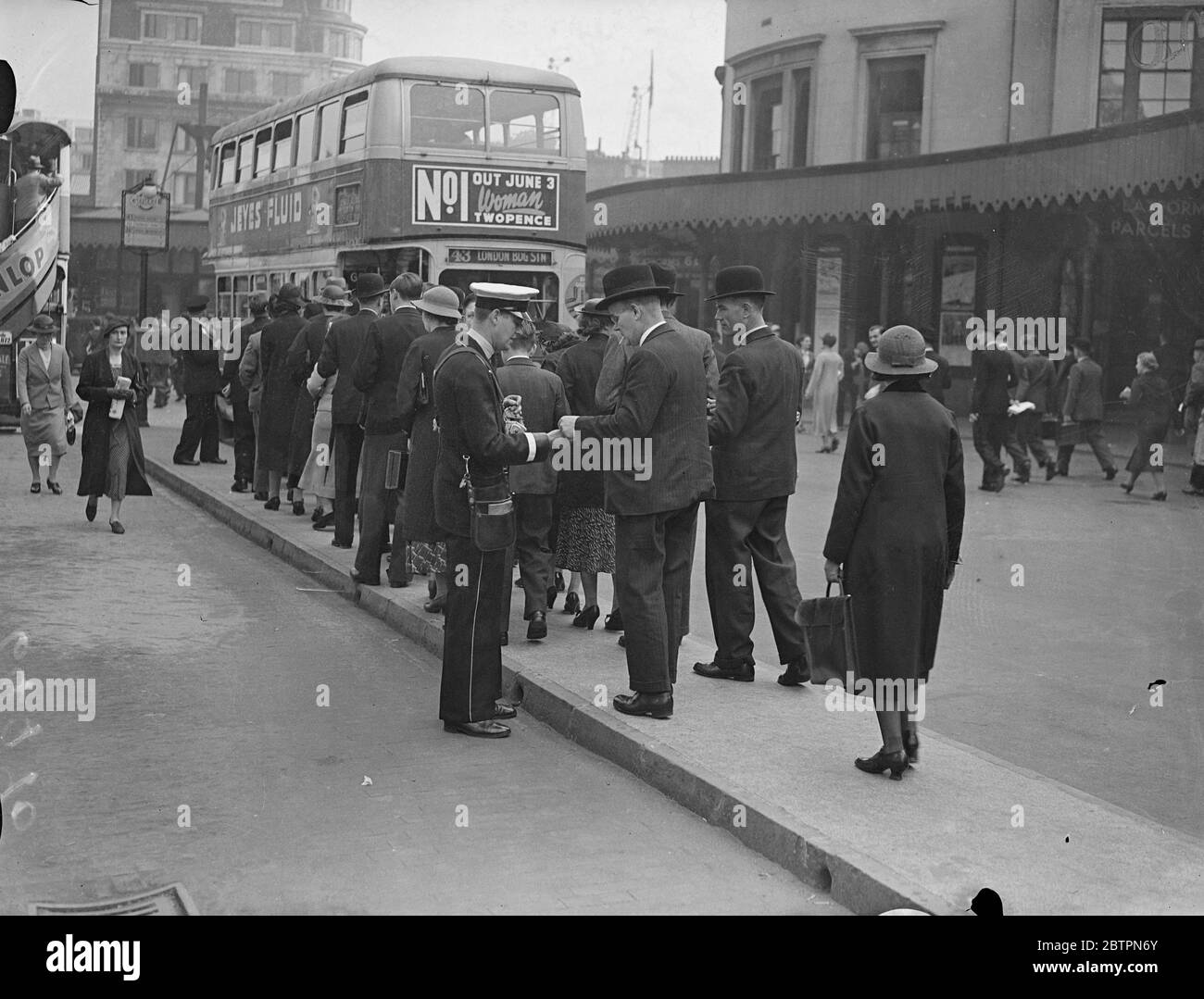 Londoners go by bus again. Thousands of eager Londoners made a dash for the buses when they reappeared after 27 day strike. Photo shows, issuing bus tickets to the queue at London Bridge. 28 May 1937 Stock Photo