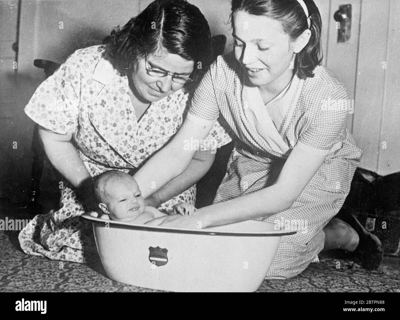 13-year-old mother bathe her baby. 'Much more fun than a doll', is the comment of Florence Rudd, aged 13, of Vallejo, California, who has just given birth to a daughter, Florence May Rudd. Photo shows, Florence Rudd, 13-year-old mother, giving her baby her first bath under the supervision of Florence's mother, Mrs Hilda May Hill 22 May 1937 Stock Photo