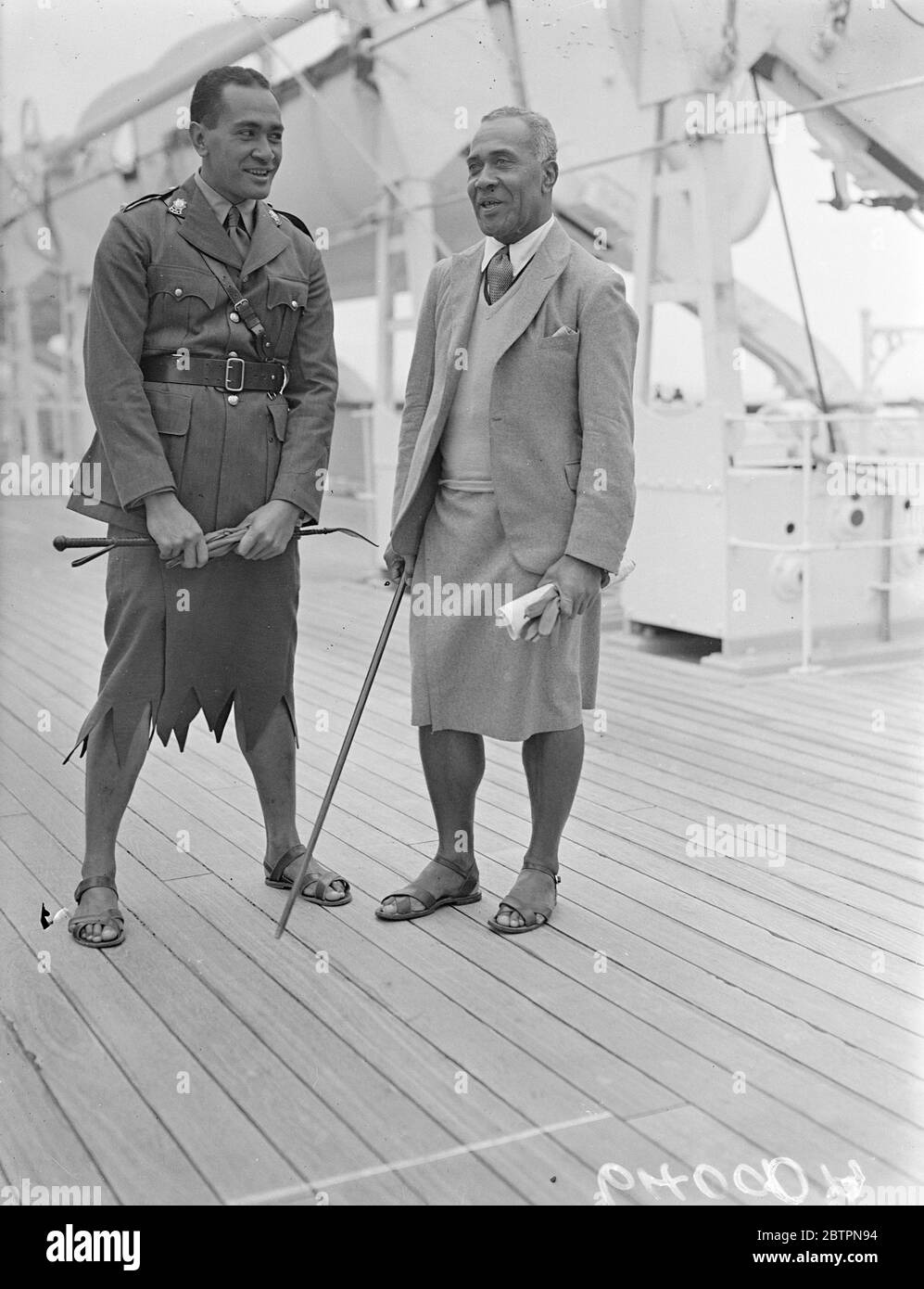 Fiji Islanders arrive for Coronation. Capt Sukuna and Lt Cakobou, of the Fiji defence force, arrived at Tilbury on the liner 'RMS Strathnaver' to represent the Fiji Islands at the Coronation. Photo shows,Lt Cakobou (who wears a skirted uniform with sandals), talking with Capt Sukuna (right) on arrival at Tilbury. 30 April 1937 Stock Photo