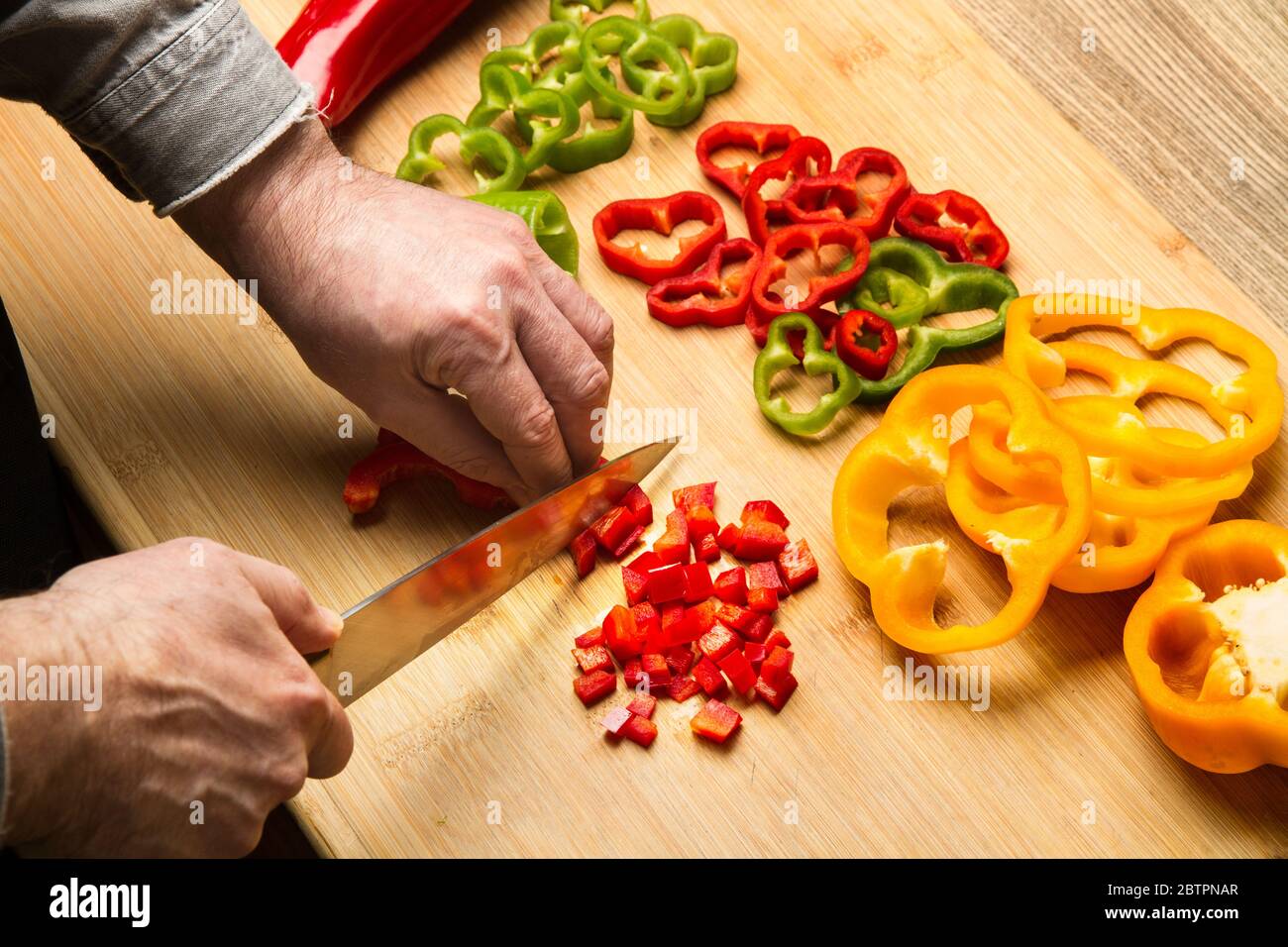 Man cutting red bell pepper on a wooden kitchen board Stock Photo Alamy
