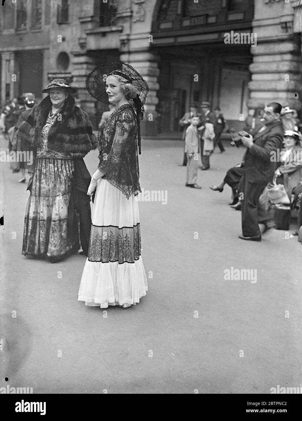 Spanish style for Ascot. Photo shows: a mantilla-like headdress worn with a lace frock by a woman racegoer leaving Waterloo Station for the second day of the Ascot meeting. 16 June 1937 Stock Photo