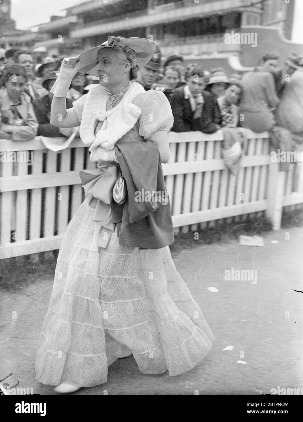 In white as Ascot. Photo shows: Picture hat, puff sleeves and flared skirt - an Ascot ensemble seen on the course on second day of the Ascot meeting. 16 June 1937 Stock Photo