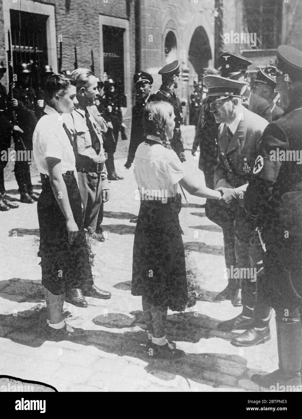 Hitler was a good listener!. Chancellor Hitler holding the arm of the Burgomaster's young daughter in a friendly handshake as he listened earnestly to her welcoming speech at Regensburg, Eastern Bavaria. During his visit to the town,Herr Hitler unveiled a bust of Anton Bruckner, the German composer, in Valhalla, and addressed a meeting of 150,000 Nazis. In his speech he dealt with disarmament. He said that Germany has become distrustful, but disarmament was not out of the question if somebody else set the example. Stock Photo