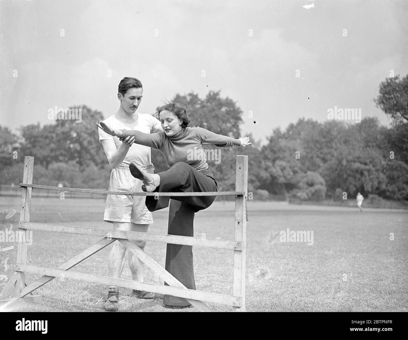 A lesson from hubby!. Mr Frederik Robert Miller, ex-Welsh rugby international, now a sports master at St Johns School, Brixton, showing his wife, Joanne, how to take a hurdle in Battersea Park, London. 19. June 1937 Stock Photo