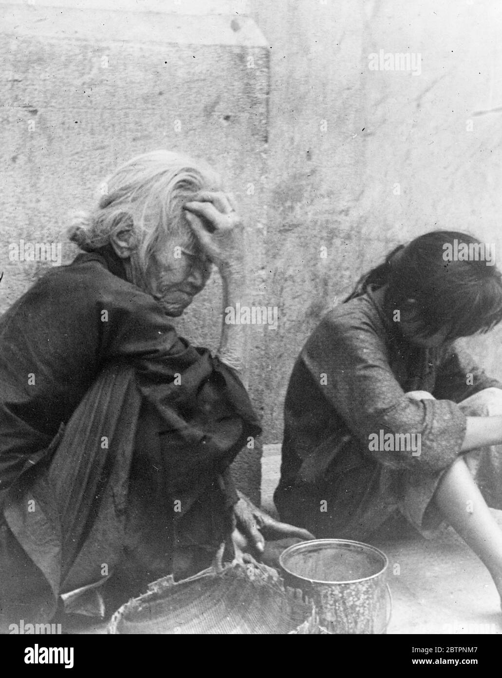 This is despair. Utter dejection, the depths of misery, touched by this old woman and a little girl whose only home is a Shanghai pavement after warplanes have rained bombs on one of the poorest quarters of the city. 27 September 1937 Stock Photo