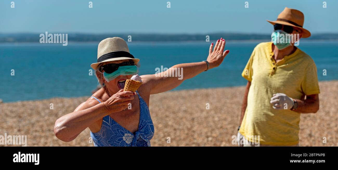 Southsea, Portsmouth, Southern England, UK. May 2020. Woman eating ice cream whilst wearing a