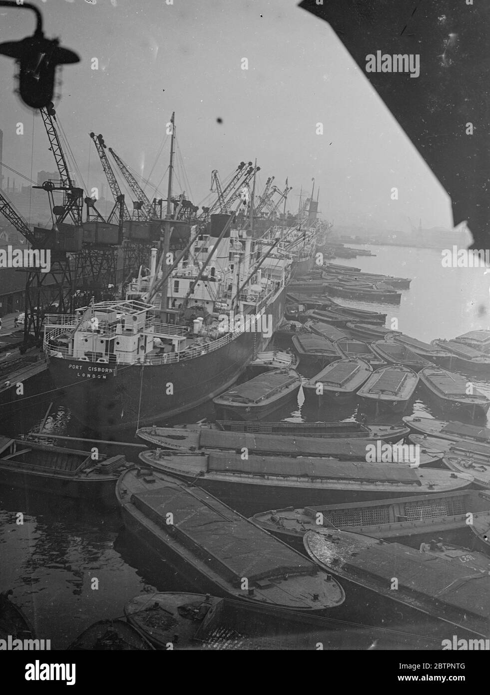 Mother and her flock!. A busy scene in the King George V Dock, London , as a fleet of barges surround the London steamer 'Port gibson' at the quayside. 24 February 1938 Stock Photo