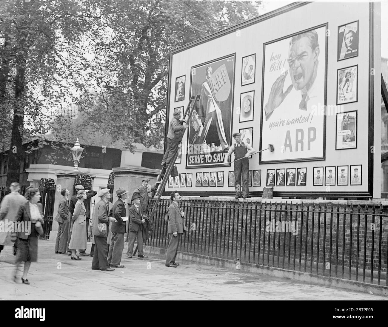 ARP volunteers still wanted. Although the prospects of settling the Sudetenland dispute are now brighter, air raid precautions work is still going on at full pressure in London as a safety measure. Photo shows, workers on their way to business paused to watch the new ARP posters being plastered up in Whitehall. 29 September 1938 Stock Photo