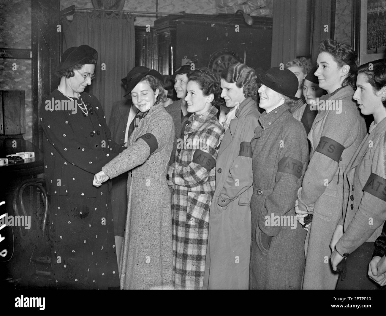 The WATS on parade. Recruits are now being enrolled for the Women's Auxiliary Territorial Service, brought into being during the recent crisis and now to be organised on the same basis as the territorial Army. Members will be used for clerical duties at the various Territorial Headquarters while Special Sections will be trained for light transport and work in cook houses and canteens. Photo shows, Company Commander Mrs Dudley Harris, issuing brassards two new recruits of the 1st County of Middlesex Company, at their headquarters at Ravenscourt Park. Armbands will be worn until the new uniforms Stock Photo