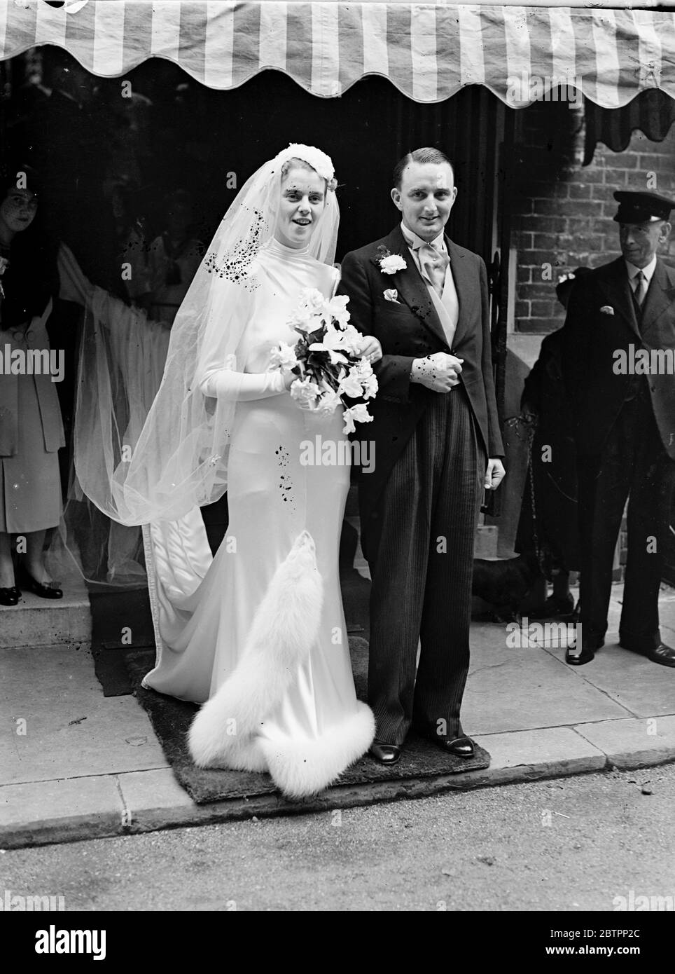 Brides fur trimmed dress. The wedding of Mr John William Banks of Pinchbeck, Spalding, Lincolnshire, and Miss Olwyn Delmar Middleton of Ealing took place at Holy Trinity Church, Brompton. Photo shows, the bride in a wedding dress edged with white fur, leaving with the bridegroom after the ceremony. 24 September 1938 Stock Photo