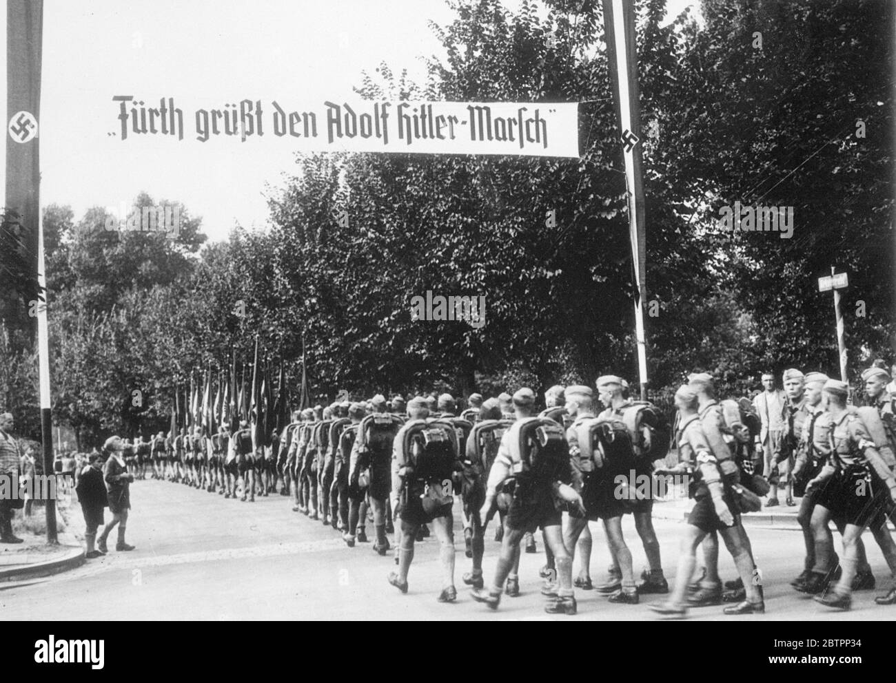 The end of the march. A column of Hitler youth marching into Furth, near Nuremberg, as they completed the 'Hitler. March'in time for the Nazi party Congress, opening at Nuremberg today (Monday). The banner across the street reads 'Furth greets the Adolf Hitler March'. 5 September 1938 Stock Photo