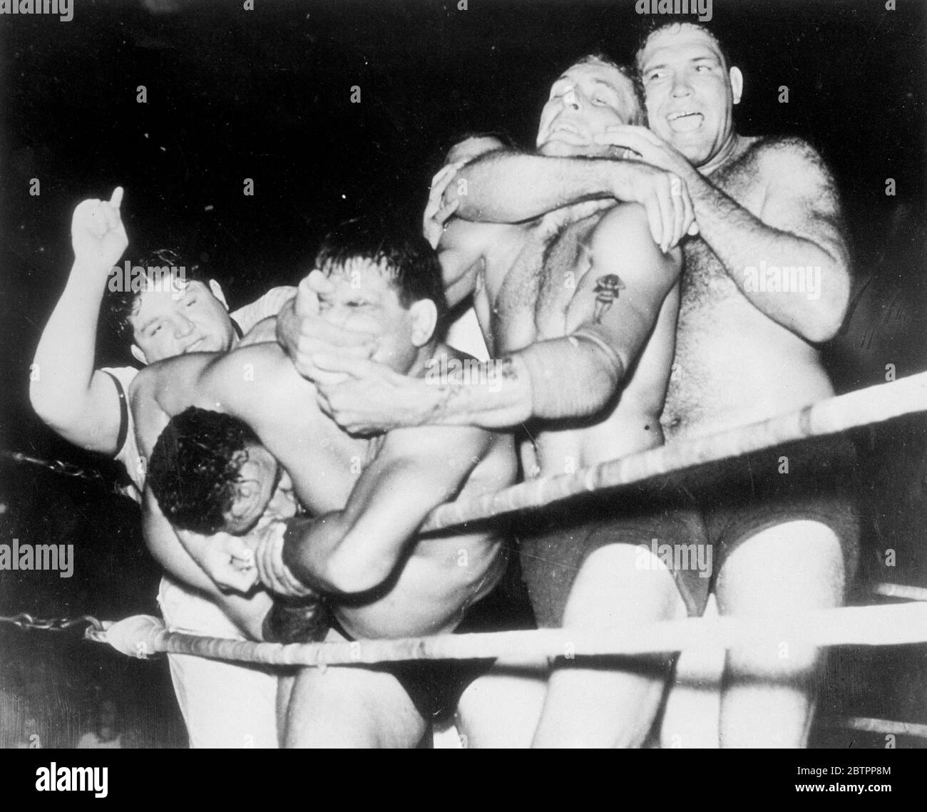 Getting to grips!. Four wrestlers doing their excellent best to strangle each other when they met in a team match at Houston, Texas. Two wrestlers named Malakoff were opposed to two others named Plummer and Davis. Judging by his expression (or what cab be seen of it) the man second from left is getting the worst of this melee. 25 July 1938 Stock Photo