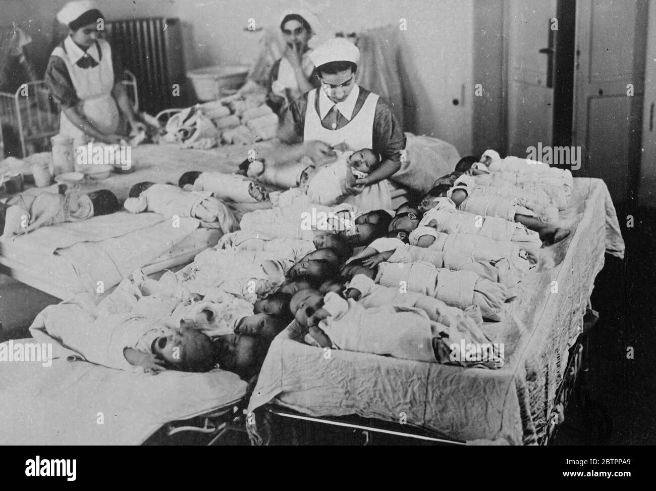 They have victories to win!. A recently arrived hatch of tiny Italian citizens making themselves heard as nurses tie them up neatly in their swaddling clothes at the Obstetric Clinic of the Polyclinic in Rome. According to Signor Mussolini 'only big families yield the big battalions, without which victories are not won'. Modern clinics for mothers and children play an important part in the 'more babies' campaign which the Italian dictator is constantly waging and which, with the announcement of a rise in the birth rate, now appears to be succeeding. 29 January 1938 Stock Photo
