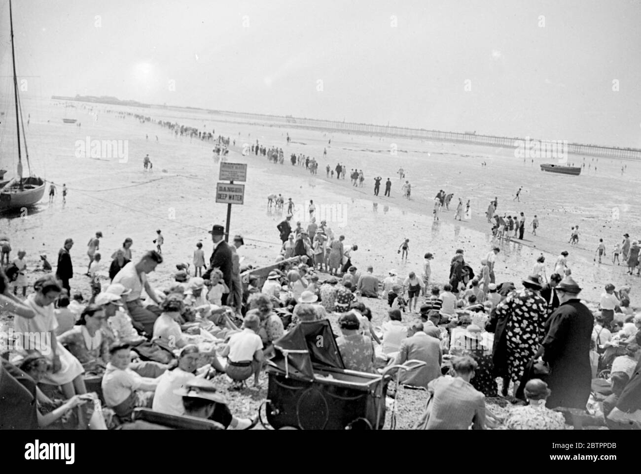 Looking for drops of sea!. With the temperature way up in the eighties, the tide has chosen this week to be out for most of the day at Southend, Essex. Consequently thousands of Southend's visitors can be seen wandering over the mud looking for puddles in which to keep cool. 4 August 1938 Stock Photo