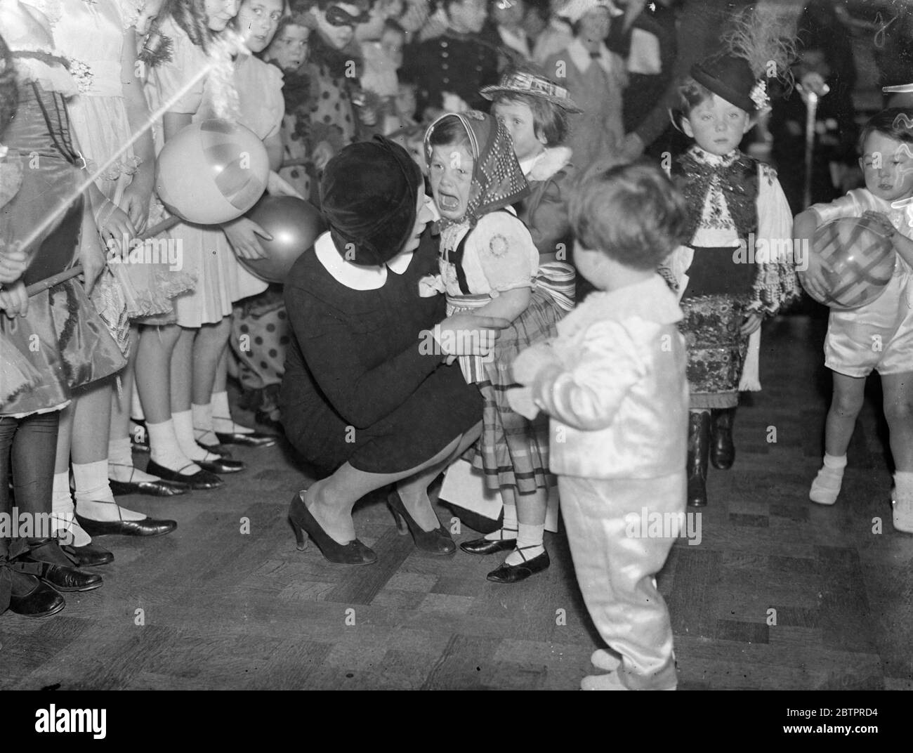 Guest lost the party spirit. A small guest, who became scared, burst into tears and had to be comforted during the costume parade at the 18th annual 'Peter Pan' fancy dress party at Claridges, London. The party was given in aid of Dr Barnardo's Homes. 6 January 1938 Stock Photo