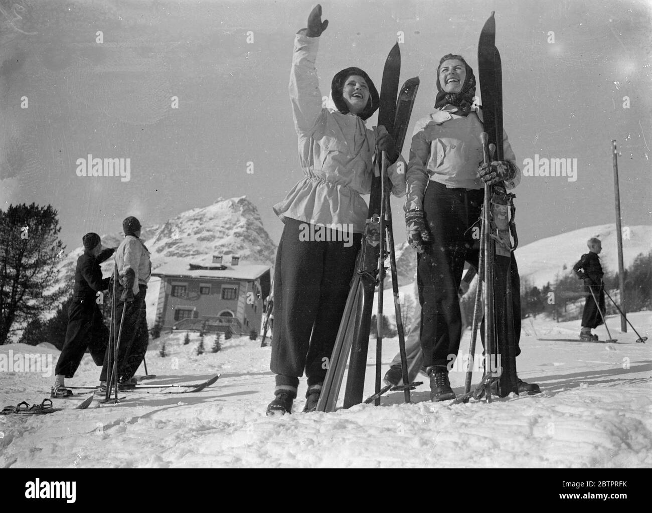 hail to the snow!. Two girls skiers send a laughing welcome across the snow as they set out for the mornings sport at St Moritz, Switzerland. They are Miss Eleanor Crocket of Hopedale, Massachusetts (USA) and Miss Elizabeth Schiltz , from Canton, Ohio. 30 December 1937 Stock Photo